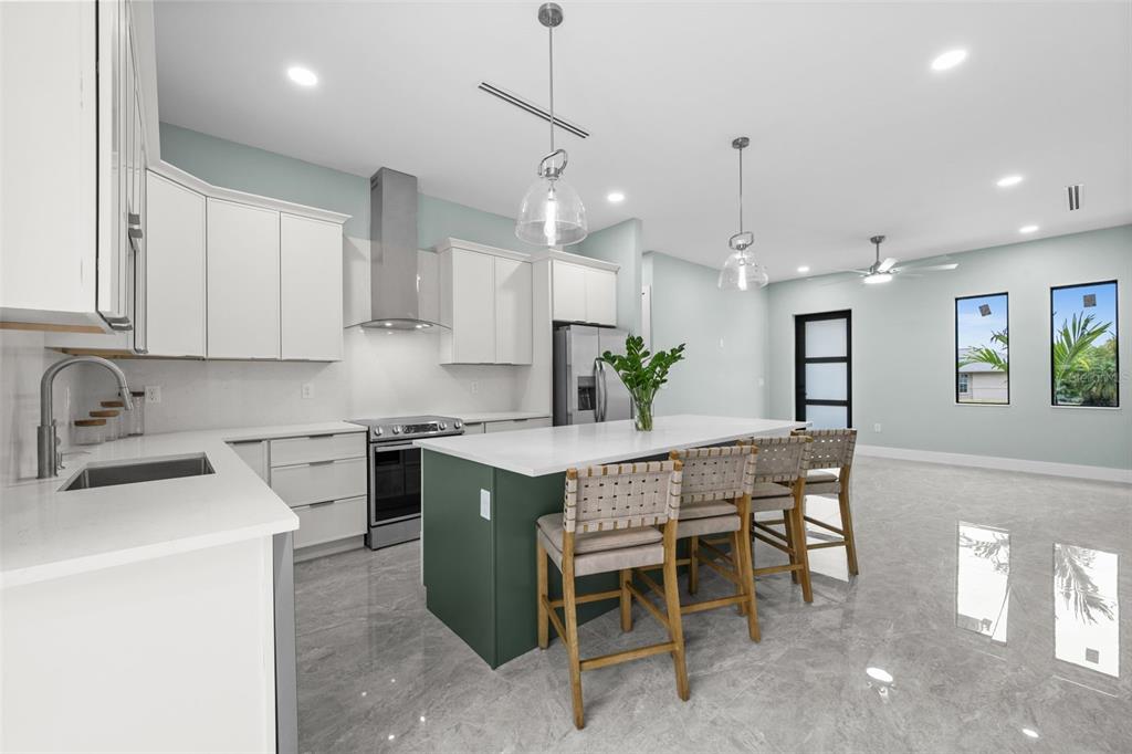A modern kitchen features white cabinetry, a green island, stainless steel appliances, and tile flooring — 16264 HORIZON ROAD, NORTH FORT MYERS, FL