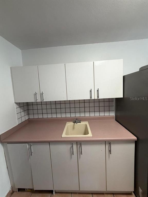 A small kitchen features white cabinets, a pink countertop, and a beige drop-in sink — A-500 LAS VILLAS DE CIUDAD JARDIN DEV. UNIT 229, BAYAMON, PR