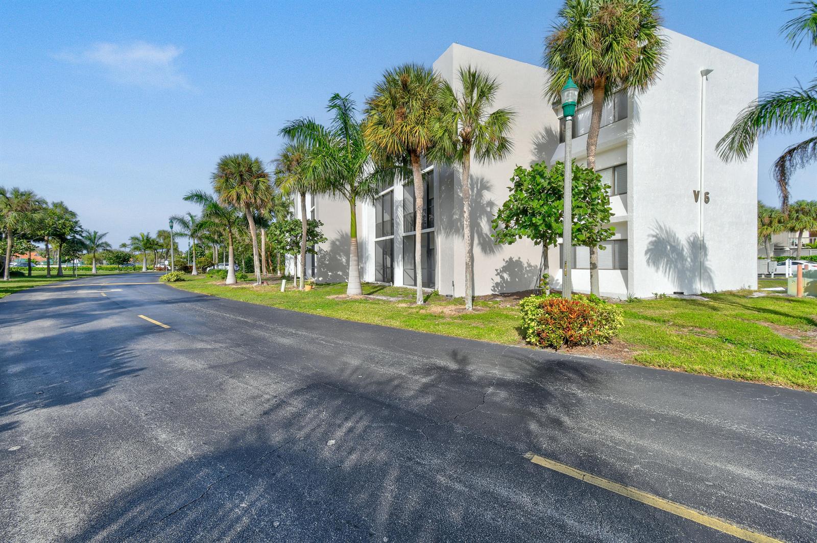 A paved road leads to a white multi-story building surrounded by palm trees — 1605 S Us Highway 1 # V6, Jupiter FL 33477, JUPITER, FL