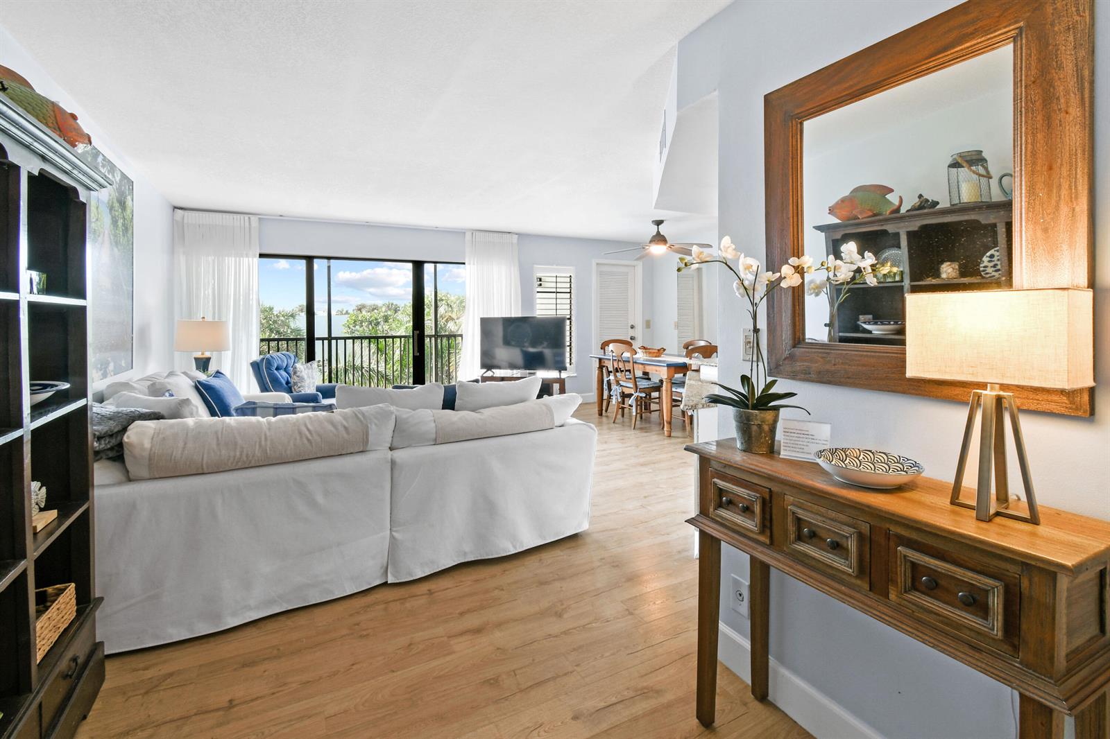 A living room with a white sectional sofa, wood flooring, and a wooden console table — 1605 S Us Highway 1 # V6, Jupiter FL 33477, JUPITER, FL
