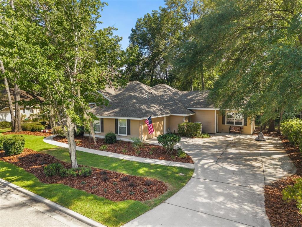 A single-story house with tan siding, a shingled roof, and a concrete driveway — 9710 SW 33RD LANE, GAINESVILLE, FL