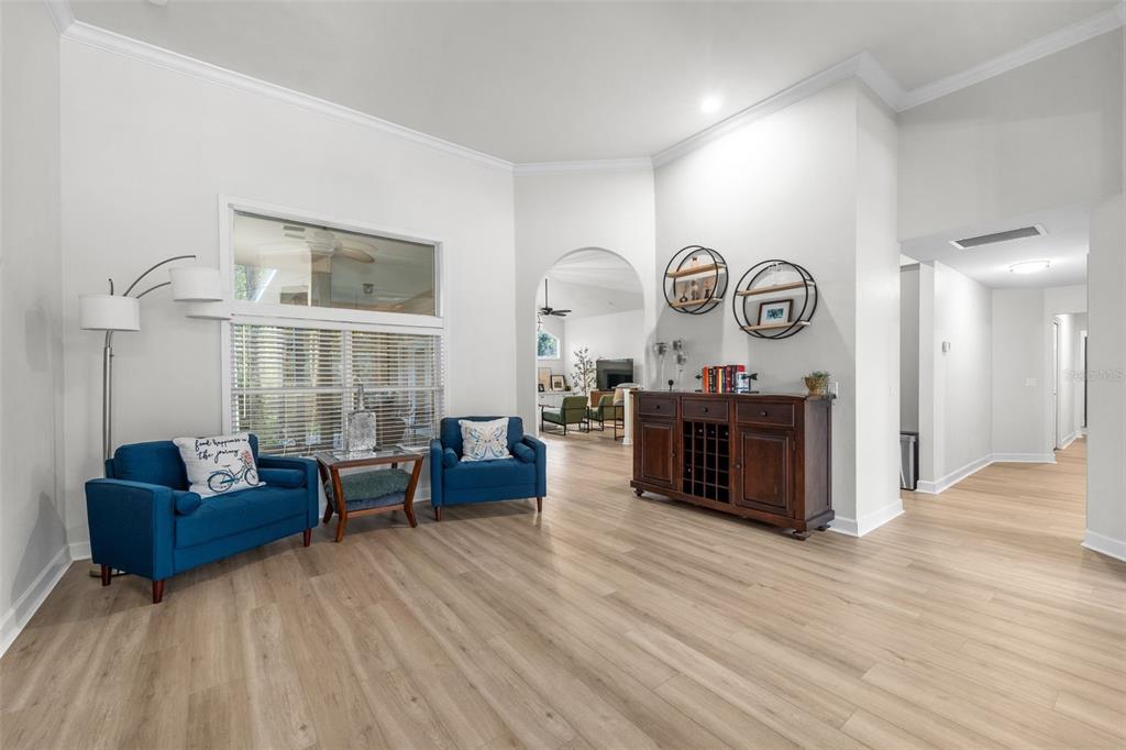 A living room features light wood flooring, blue seating, and a dark wood console table — 9710 SW 33RD LANE, GAINESVILLE, FL