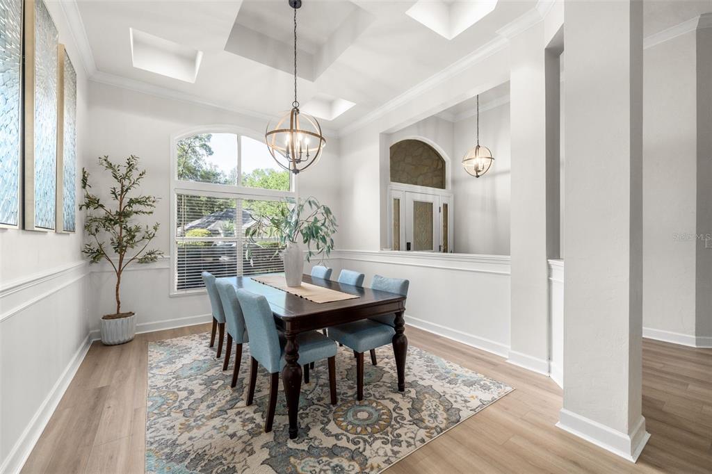 A dining room features a dark wood table, light blue chairs, and a patterned rug — 9710 SW 33RD LANE, GAINESVILLE, FL