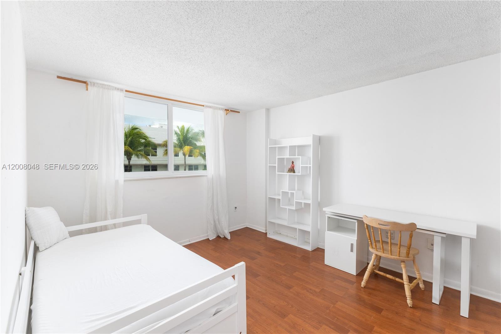 A bedroom features white walls, wood flooring, a white bed, a desk, and a bookshelf — 345 Ocean Dr # 304, Miami Beach FL 33139, MIAMI BEACH, FL