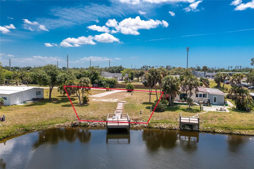 An aerial view shows a vacant waterfront lot with a wooden dock and red boundary lines — 6371 FALCON DRIVE UNIT 12, ENGLEWOOD, FL