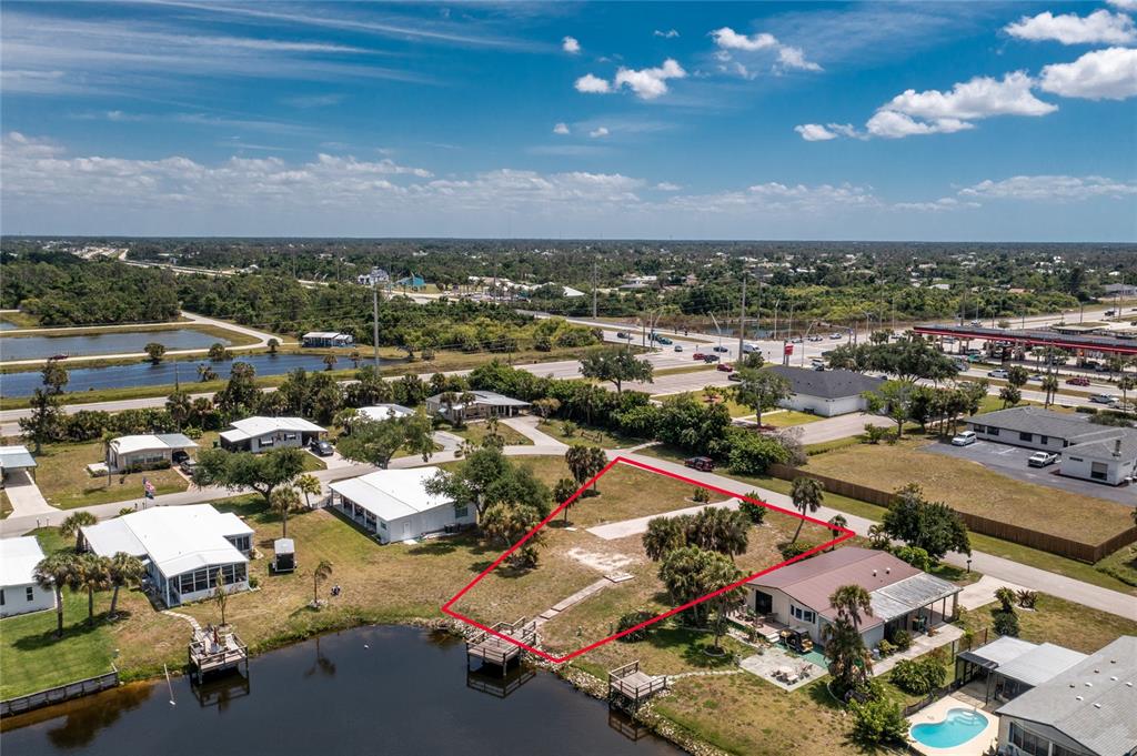 An aerial view shows a vacant waterfront lot outlined in red next to existing homes — 6371 FALCON DRIVE UNIT 12, ENGLEWOOD, FL