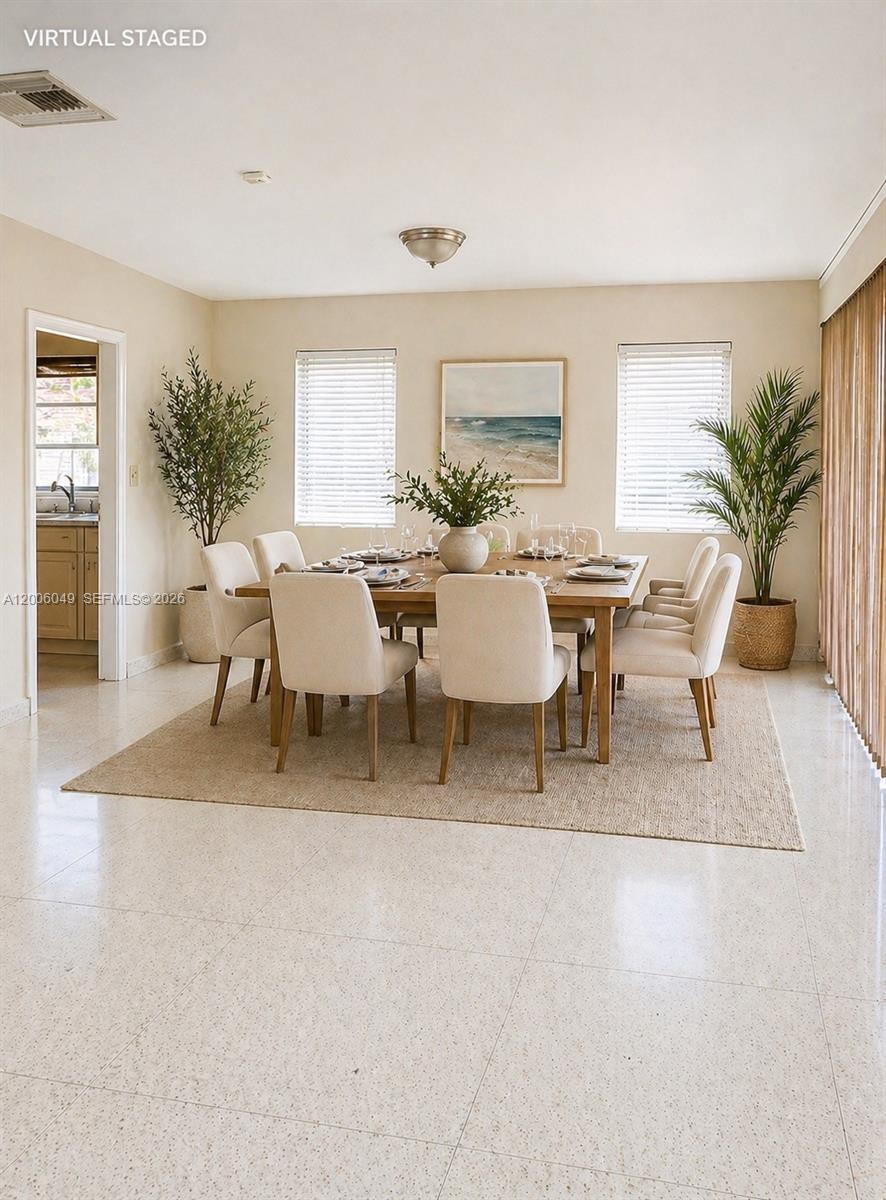 This dining room features a wooden table, upholstered chairs, a rug, and two potted plants — 9205 Byron Ave, Surfside FL 33154, SURFSIDE, FL
