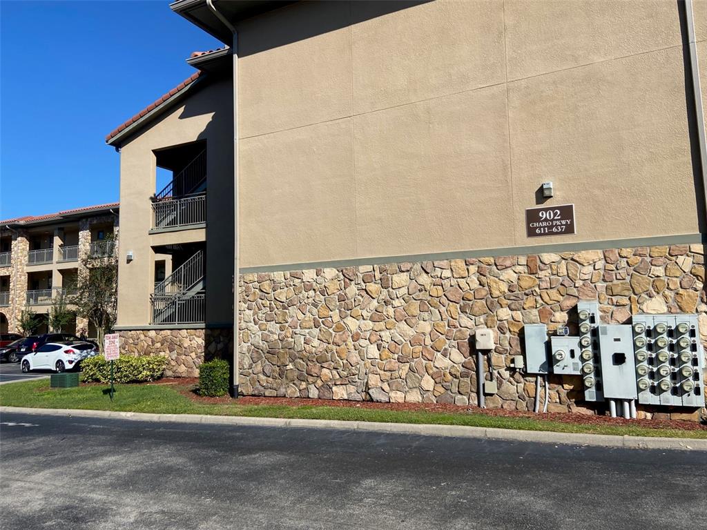 An exterior view of a multi-story apartment building with stone veneer and utility meters — 902 CHARO PARKWAY UNIT 622, DAVENPORT, FL