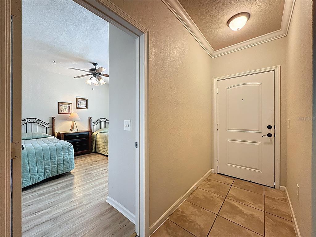 A tiled entryway leads into a bedroom with two beds and light wood-look flooring — 902 CHARO PARKWAY UNIT 622, DAVENPORT, FL