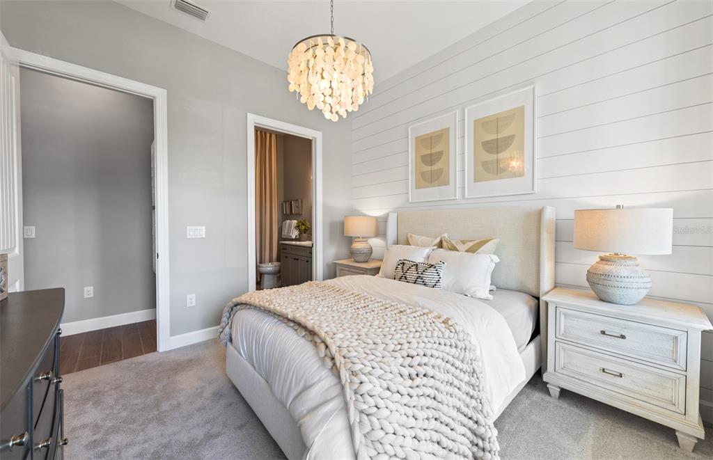 A bedroom features a shiplap accent wall, a shell chandelier, and a neutral-toned bed — 1758 PEPPER GRASS DRIVE, NORTH PORT, FL