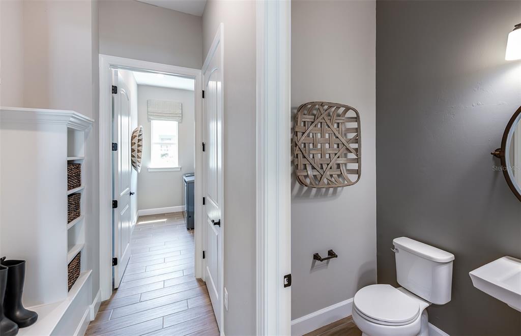 A hallway with wood-look tile flooring leads to a laundry room beside a small bathroom — 1758 PEPPER GRASS DRIVE, NORTH PORT, FL