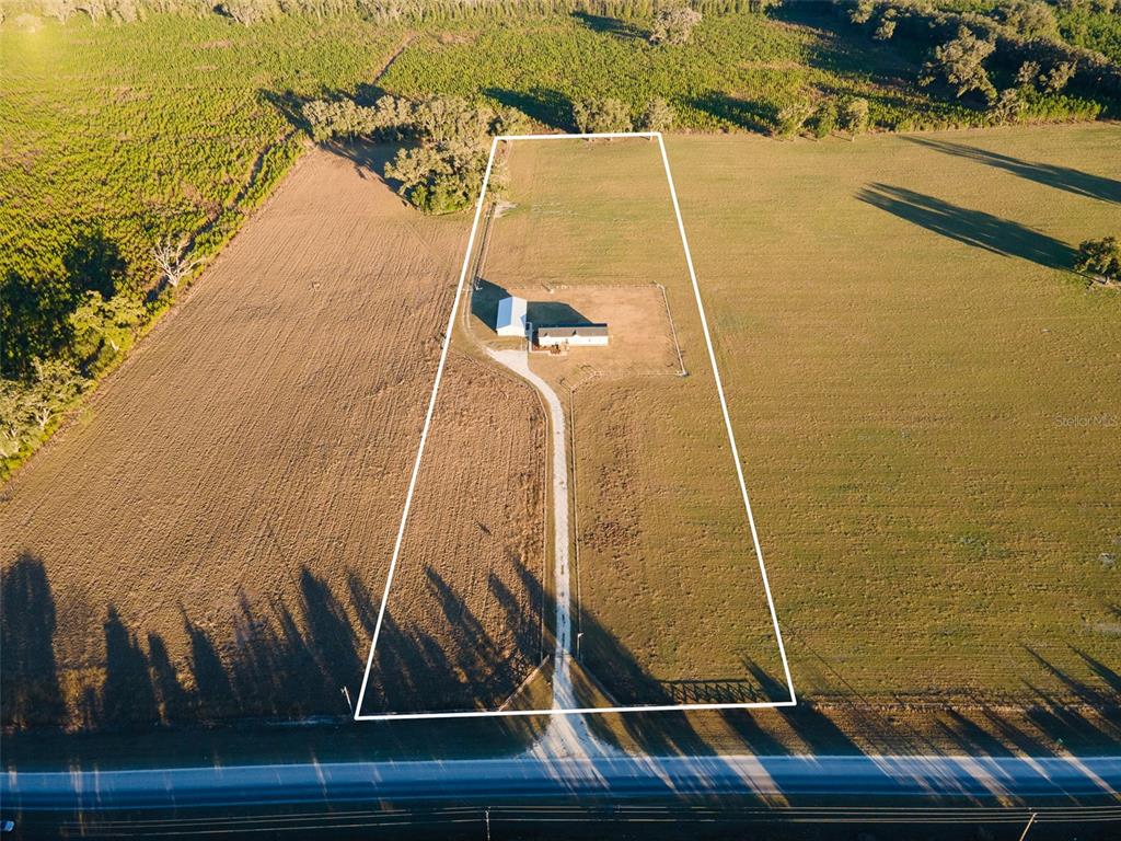 An aerial view shows a house and outbuilding on a large, fenced rural property — 3789 NW 202ND STREET, NEWBERRY, FL