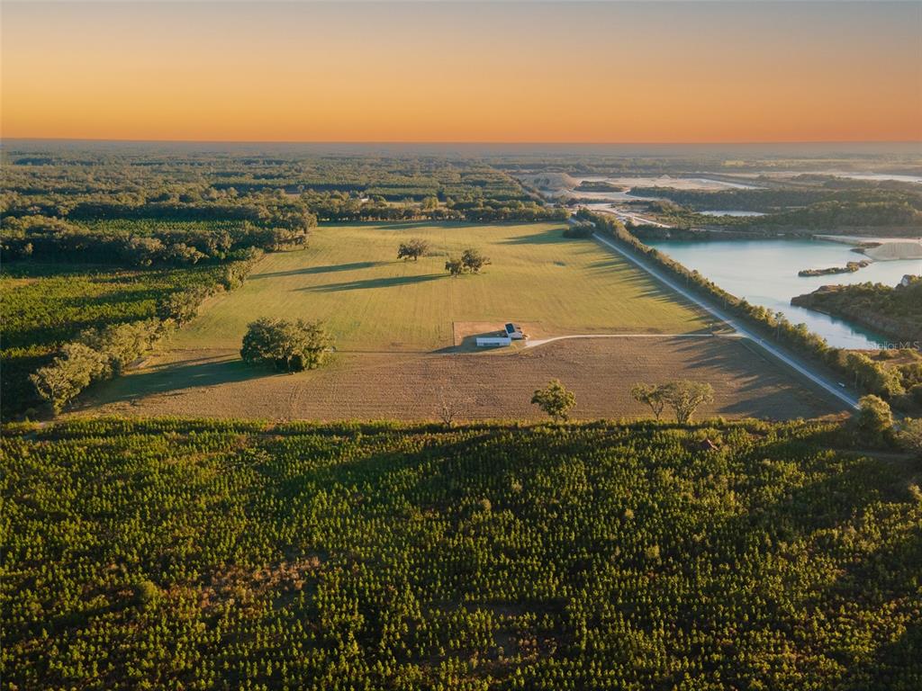 An aerial view shows a rural property with a house, open fields, and a lake — 3789 NW 202ND STREET, NEWBERRY, FL