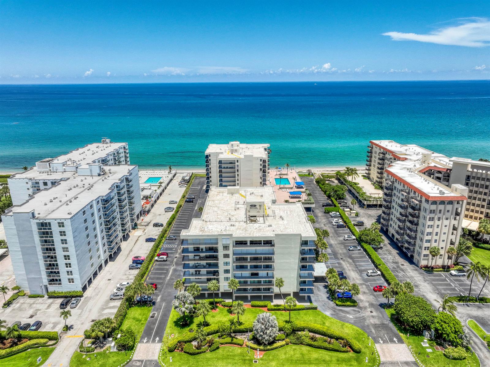 An aerial view shows three multi-story apartment buildings with parking lots and pools near the ocean — 3460 S Ocean Boulevard # 612, Palm Beach FL 33480, PALM BEACH, FL
