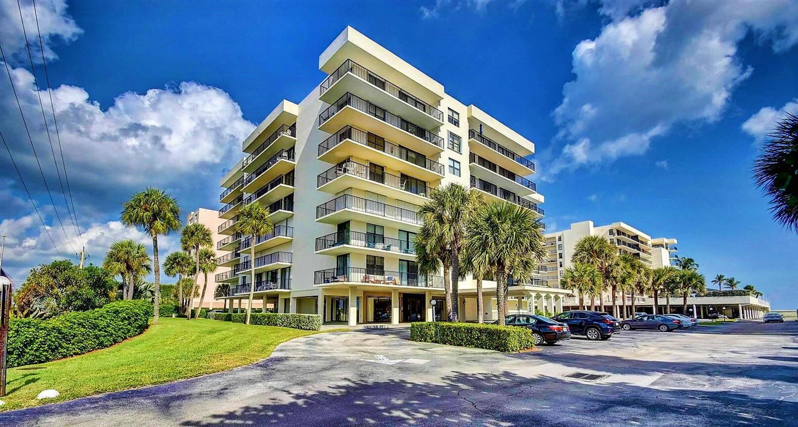 A multi-story residential building with balconies and a parking lot under a blue sky — 3460 S Ocean Boulevard # 612, Palm Beach FL 33480, PALM BEACH, FL