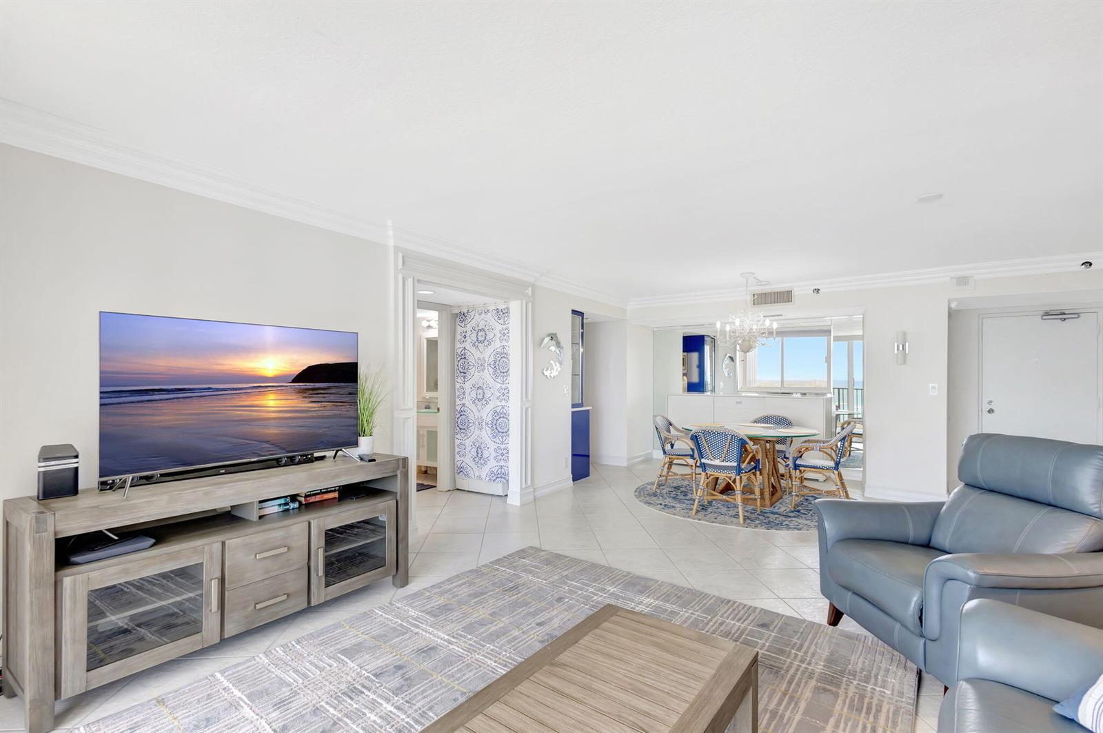 A living room with a television, a dining area, and tile flooring — 300 Ocean Trail Way # 907, Jupiter FL 33477, JUPITER, FL
