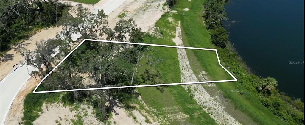 An aerial view of a vacant, tree-covered residential lot bordering a body of water — 149 TRANQUIL MIRROR LAKE COURT Lot 12, CLERMONT, FL
