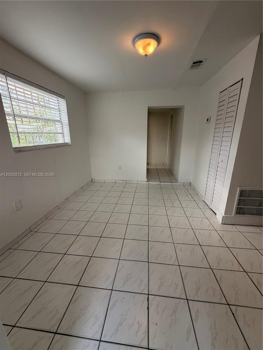 A room with white tile floors, a window with blinds, and a closet with louvered doors — 2420 NW 31st St # 3, Miami FL 33142, MIAMI, FL