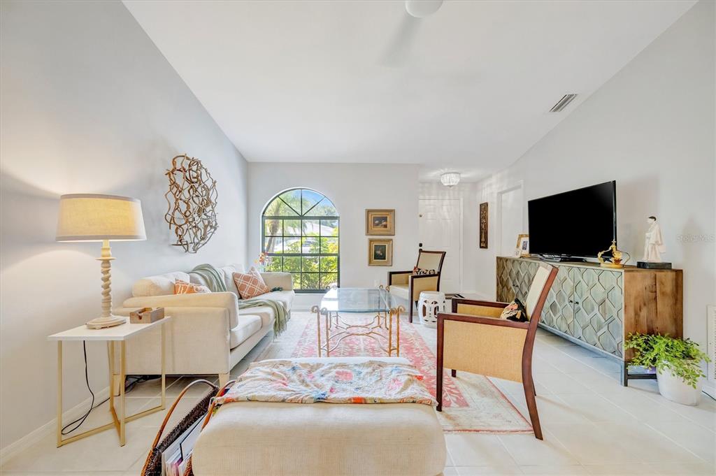 A living room features a white sofa, two armchairs, a glass coffee table, and television — 5872 PAUMA COURT, SARASOTA, FL