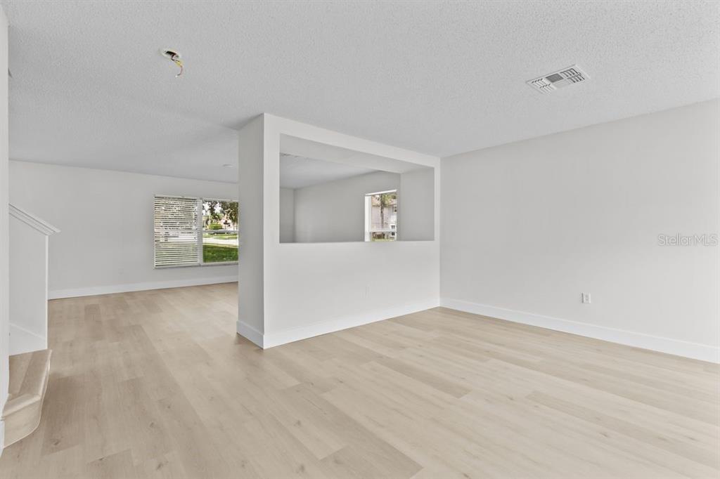 An interior view of a living area featuring light wood-look flooring and a pass-through wall — 1537 MORNING STAR DRIVE, CLERMONT, FL