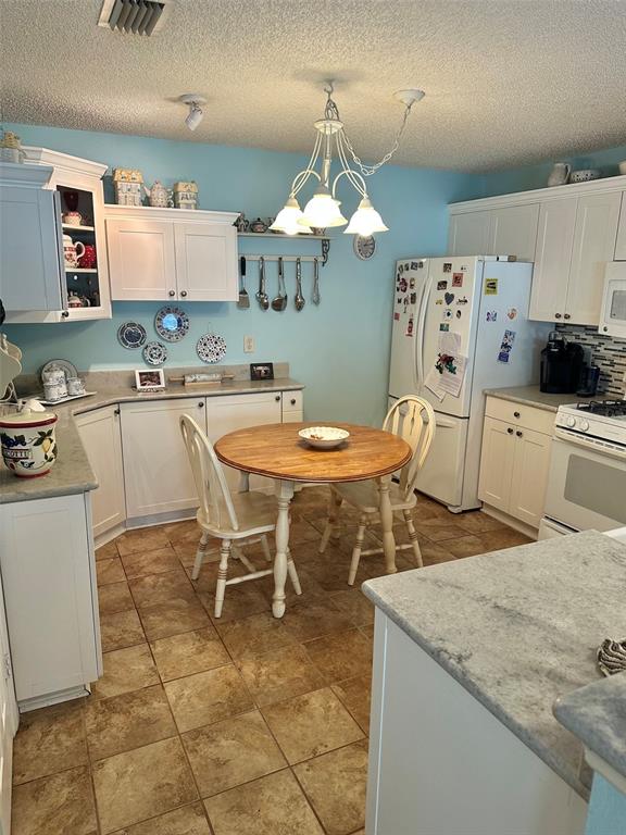 A kitchen with white cabinets, light blue walls, a round wooden table, and tile flooring — 17350 SE 77TH SYCAMORE AVENUE, THE VILLAGES, FL