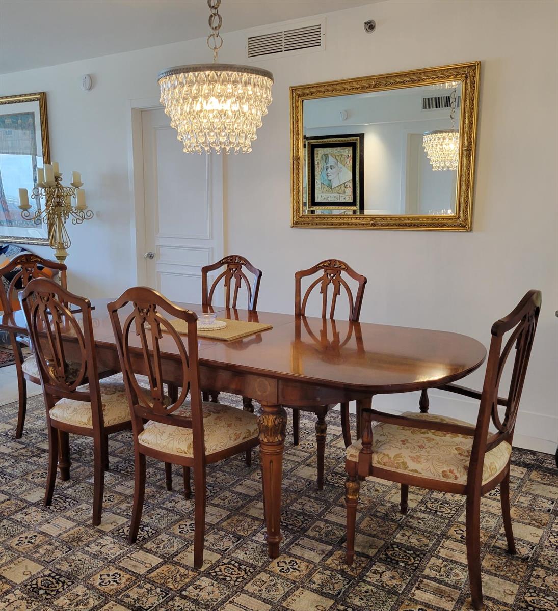 A formal dining room features a wooden table, six chairs, a crystal chandelier, and a mirror — 1830 S Ocean Drive # 5111, FL 33009, FL