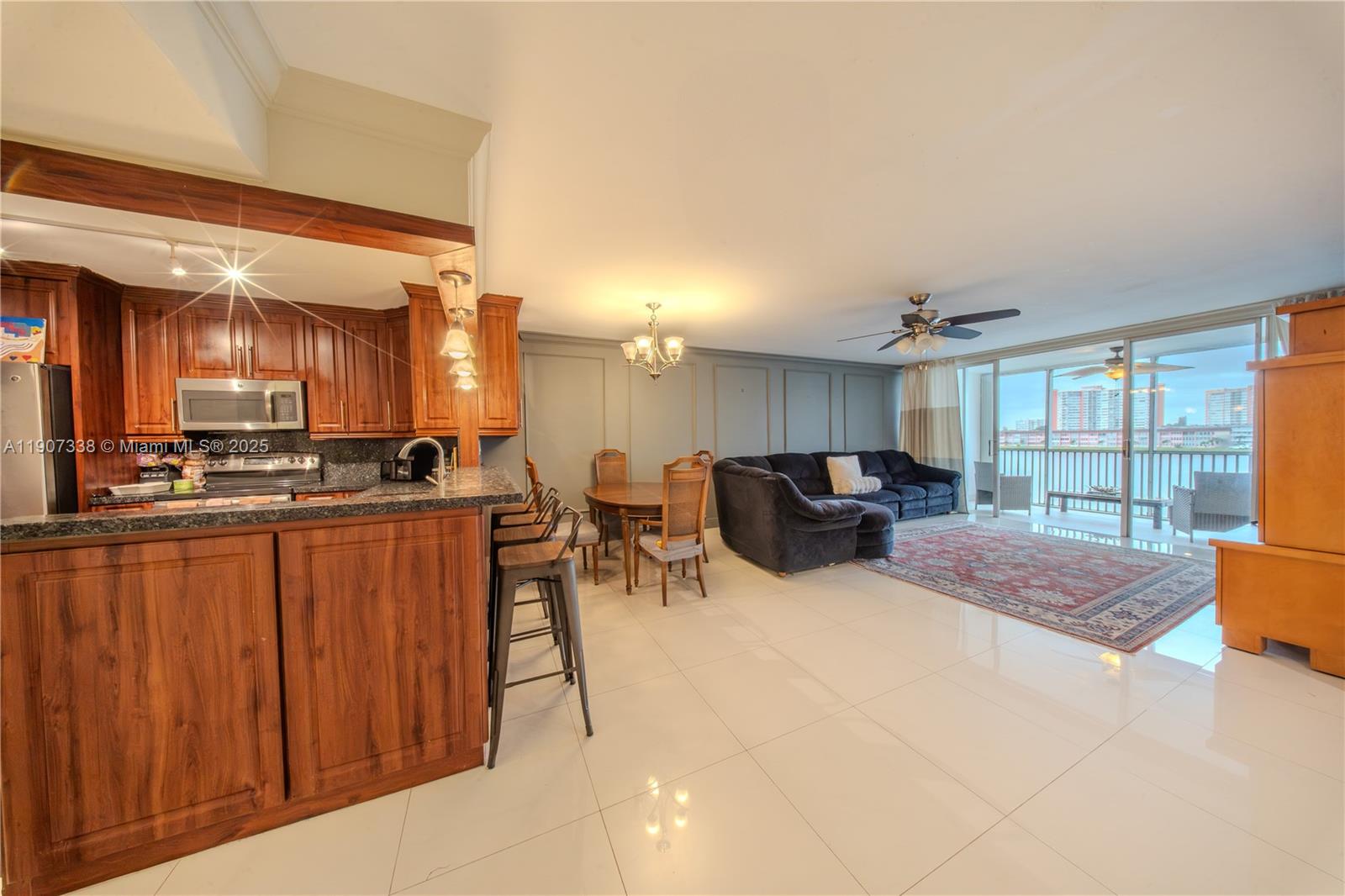 An open-concept living area features a wooden kitchen island, dining set, and balcony access — 1660 NE 191st St # 1, Miami FL 33179, MIAMI, FL