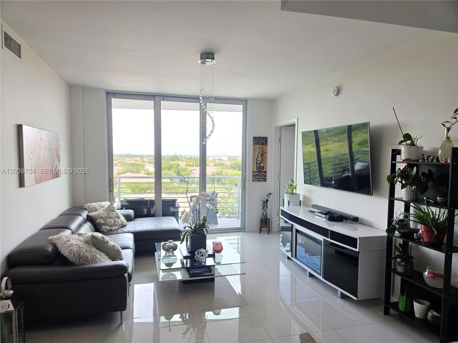 A modern living room features a grey sectional sofa, glass coffee table, and balcony view — 7875 NW 107th Ave # 510, Doral FL 33178, DORAL, FL