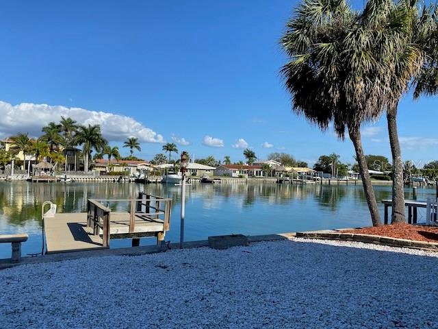 A wooden dock extends into a calm canal lined with houses and palm trees — 11975 3RD STREET E UNIT 6, TREASURE ISLAND, FL