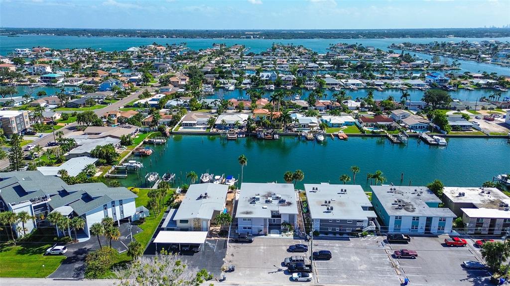 An aerial view shows waterfront residential buildings, boat docks, and a parking lot — 11975 3RD STREET E UNIT 6, TREASURE ISLAND, FL