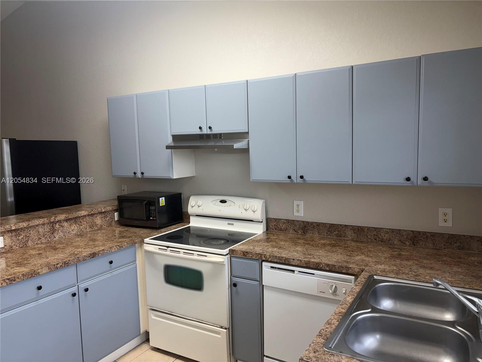 A kitchen features light blue cabinets, brown laminate countertops, and white appliances — 4545 26TH ST SW # 0, Lehigh Acres FL 33973, LEHIGH ACRES, FL