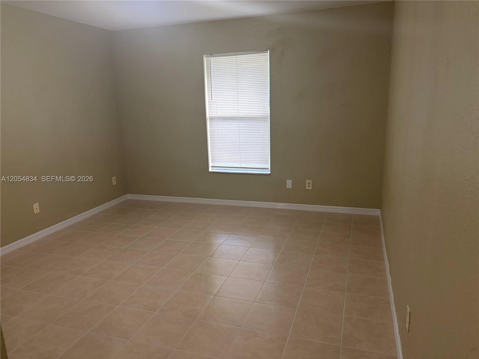 An empty room features beige walls, a single window with blinds, and tiled flooring — 4545 26TH ST SW # 0, Lehigh Acres FL 33973, LEHIGH ACRES, FL