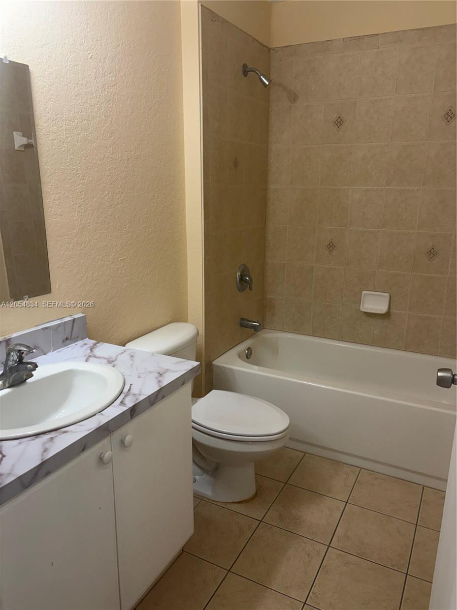 A bathroom features a vanity with a marble-patterned countertop, a toilet, and a tiled tub — 4545 26TH ST SW # 0, Lehigh Acres FL 33973, LEHIGH ACRES, FL