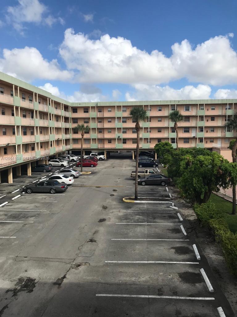 An exterior view of a multi-story apartment building with a parking lot in front — 1655 W 44th Pl # 304, Hialeah FL 33012, HIALEAH, FL