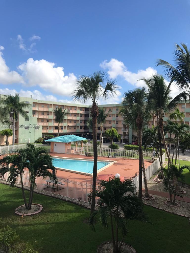 An outdoor swimming pool with a covered patio area sits in front of an apartment building — 1655 W 44th Pl # 304, Hialeah FL 33012, HIALEAH, FL