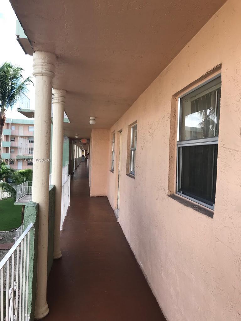 An exterior walkway with a concrete floor, white railings, and peach-colored walls — 1655 W 44th Pl # 304, Hialeah FL 33012, HIALEAH, FL