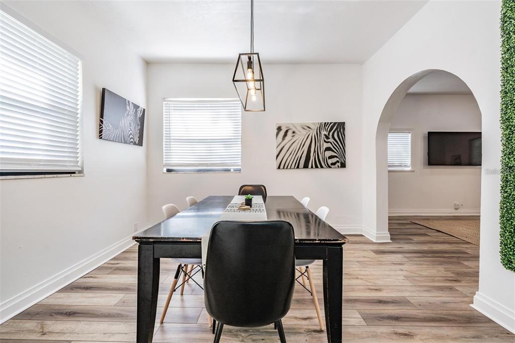 A dining room features a dark table, black chairs, zebra-print wall art, and wood flooring — 2325 W GREEN STREET, TAMPA, FL