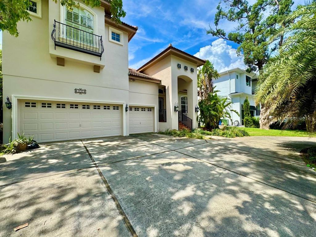 A two-story house with a three-car garage and a concrete driveway under a blue sky — 4620 W BROWNING AVENUE, TAMPA, FL