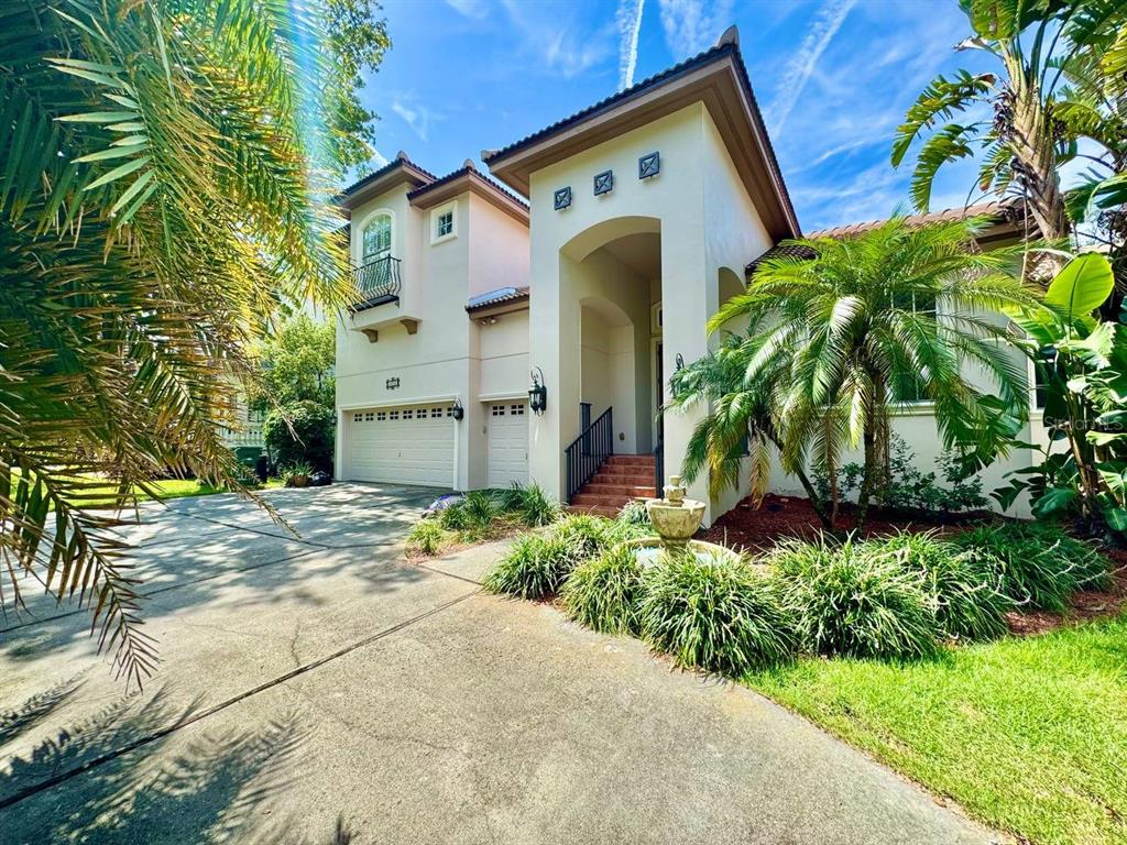 A two-story stucco house with a multi-car garage, arched entryway, and palm trees — 4620 W BROWNING AVENUE, TAMPA, FL