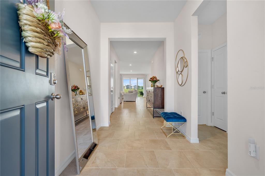 A tiled entryway leads to an open living area with a mirror and blue bench — 32516 OSPREY PEAK WAY, SAN ANTONIO, FL