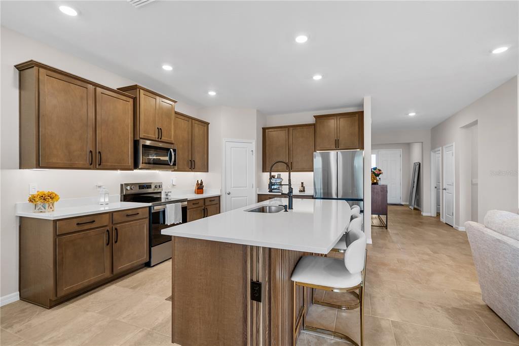 A kitchen features wood cabinets, white countertops, a central island, and stainless steel appliances — 32516 OSPREY PEAK WAY, SAN ANTONIO, FL