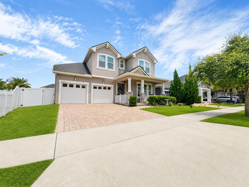 A two-story suburban house with a paved driveway, two-car garage, and a covered front porch — 8011 BUSHMASTER AVENUE, ORLANDO, FL