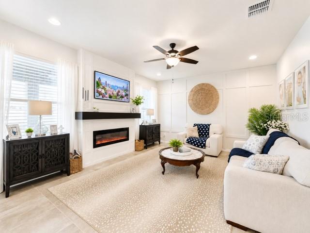 A bright living room features a fireplace, a television, and a white sofa — 8011 BUSHMASTER AVENUE, ORLANDO, FL