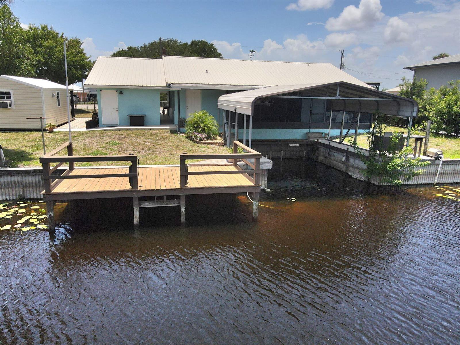 A light blue house with a metal roof, a wooden dock, and a boat slip — 1115 Elm Street, Okeechobee FL 34974, OKEECHOBEE, FL
