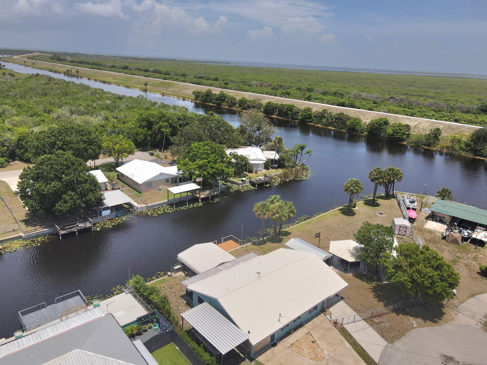 An aerial view shows waterfront houses along a canal bordered by trees and marshland — 1115 Elm Street, Okeechobee FL 34974, OKEECHOBEE, FL