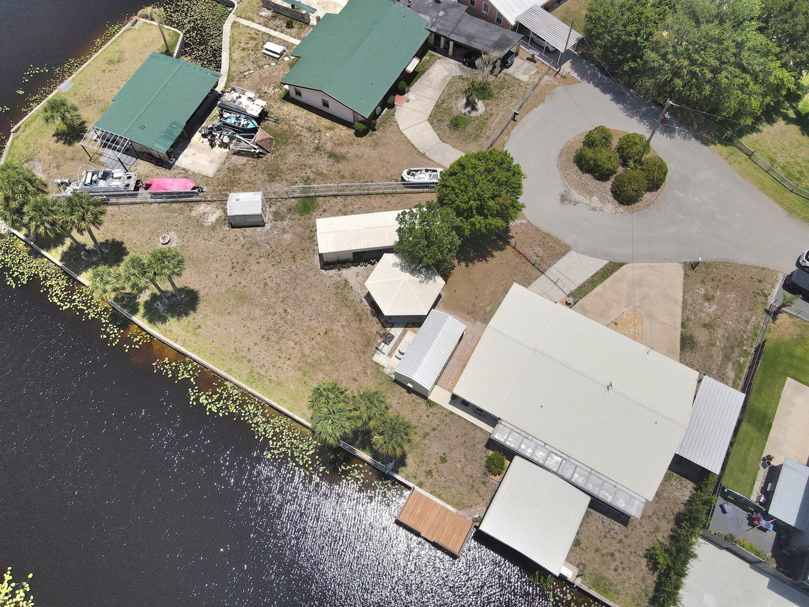 An aerial view shows multiple buildings, a circular driveway, and a dock on a lake — 1115 Elm Street, Okeechobee FL 34974, OKEECHOBEE, FL