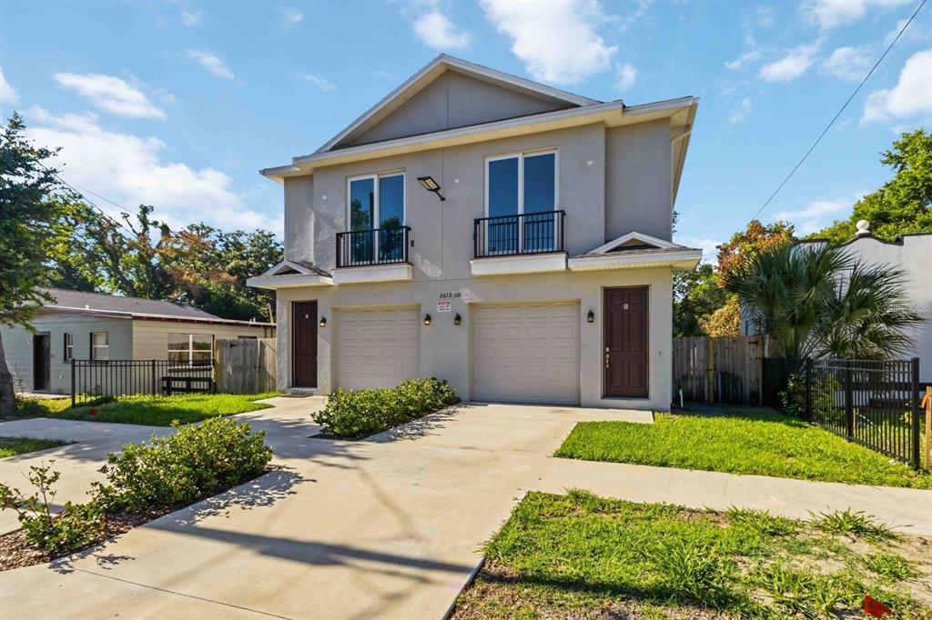 A two-story duplex with two garages, brown front doors, and small balconies on the second floor — 2613 E 23RD AVENUE UNIT 1/2, TAMPA, FL