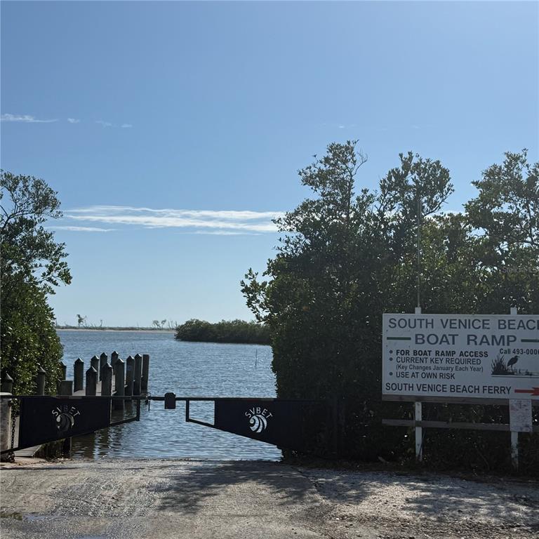 A gated boat ramp leads to a waterway surrounded by trees under a clear sky — SOUTHLAND ROAD, VENICE, FL