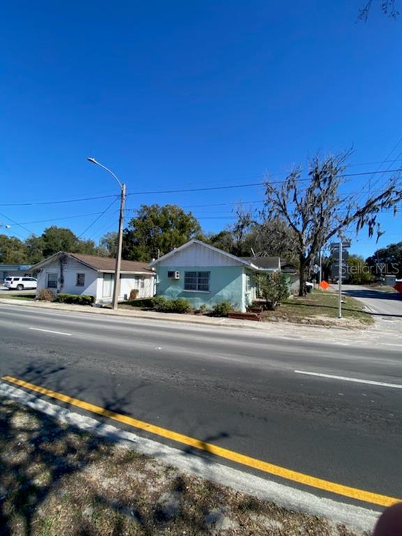 Two small, single-story houses sit along a paved road under a clear blue sky — 20371 E MCKINNEY AVENUE, DUNNELLON, FL