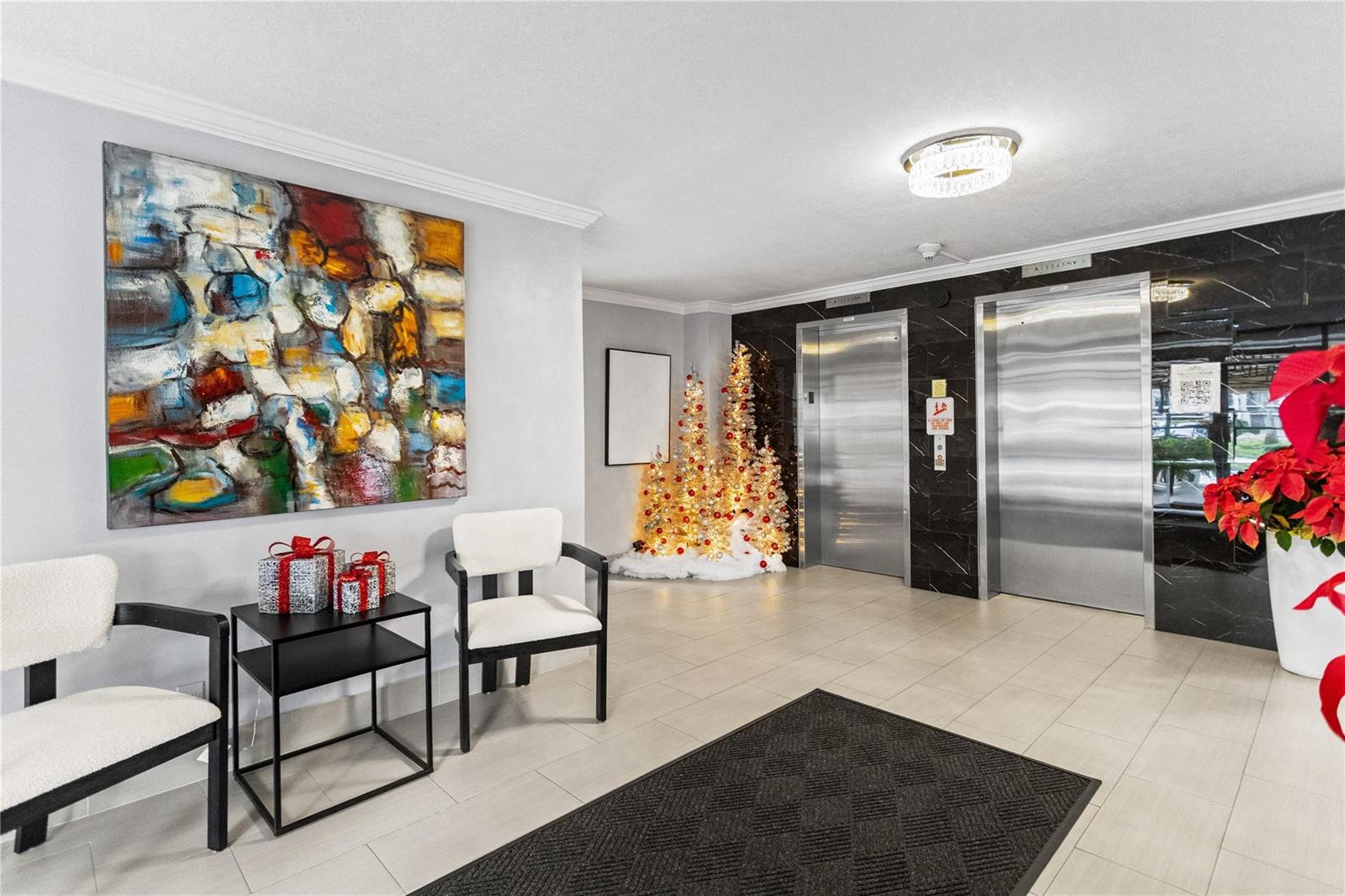 A building lobby features two elevators, white chairs, holiday decorations, and a large abstract painting — 3000 S Course Drive # 607, Pompano Beach FL 33069, POMPANO BEACH, FL